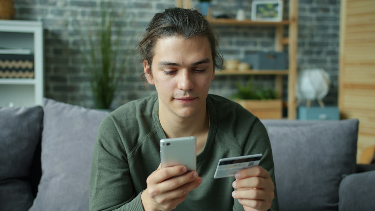 Customer using a smartphone and payment card to shop online